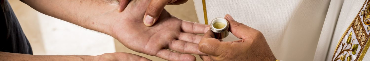 Sacraments of the Catholic Christian religion in church. Hands of a Catholic Priest applying the oil for the Anointing of the Sick. Sacraments of the Catholic Christian religion in church.